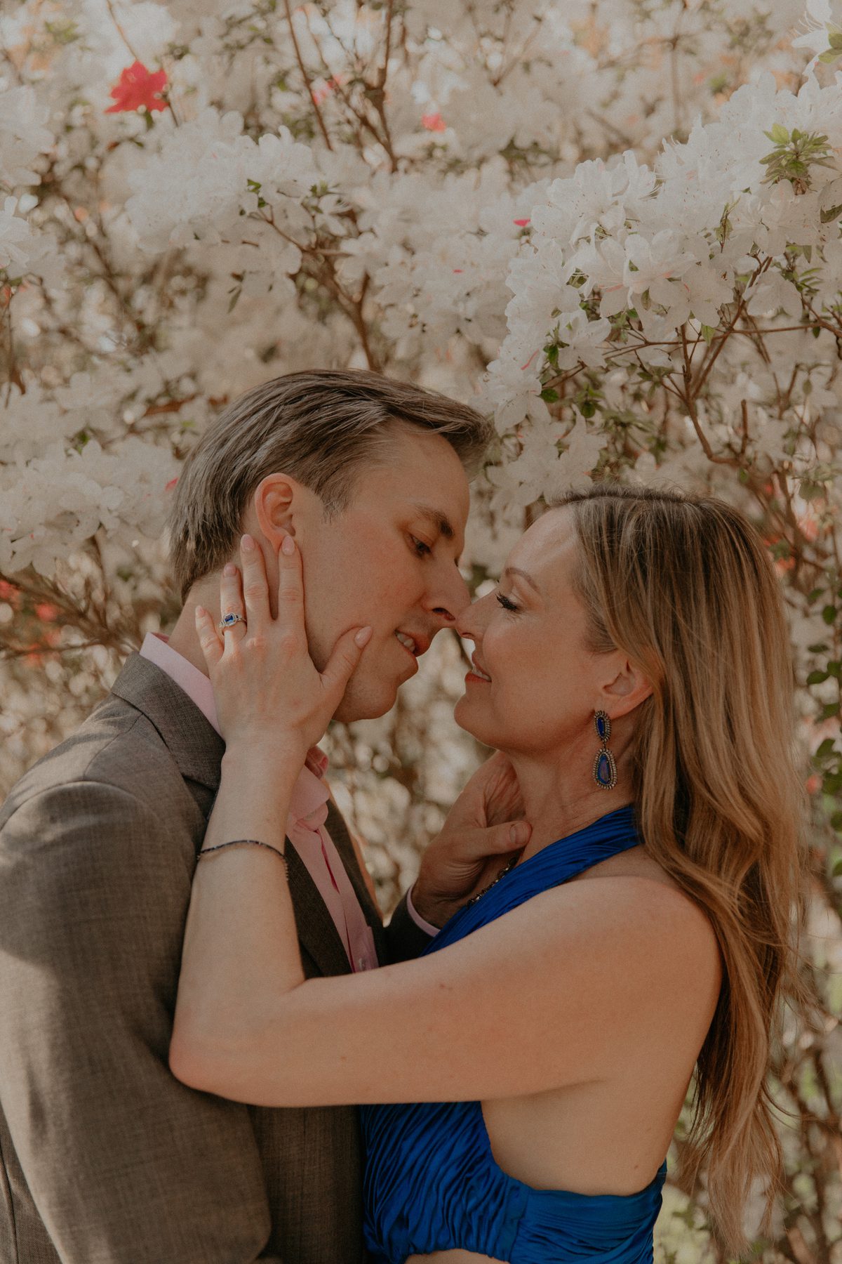 Kimberly and Ian nose to nose in front of white azalea blossoms