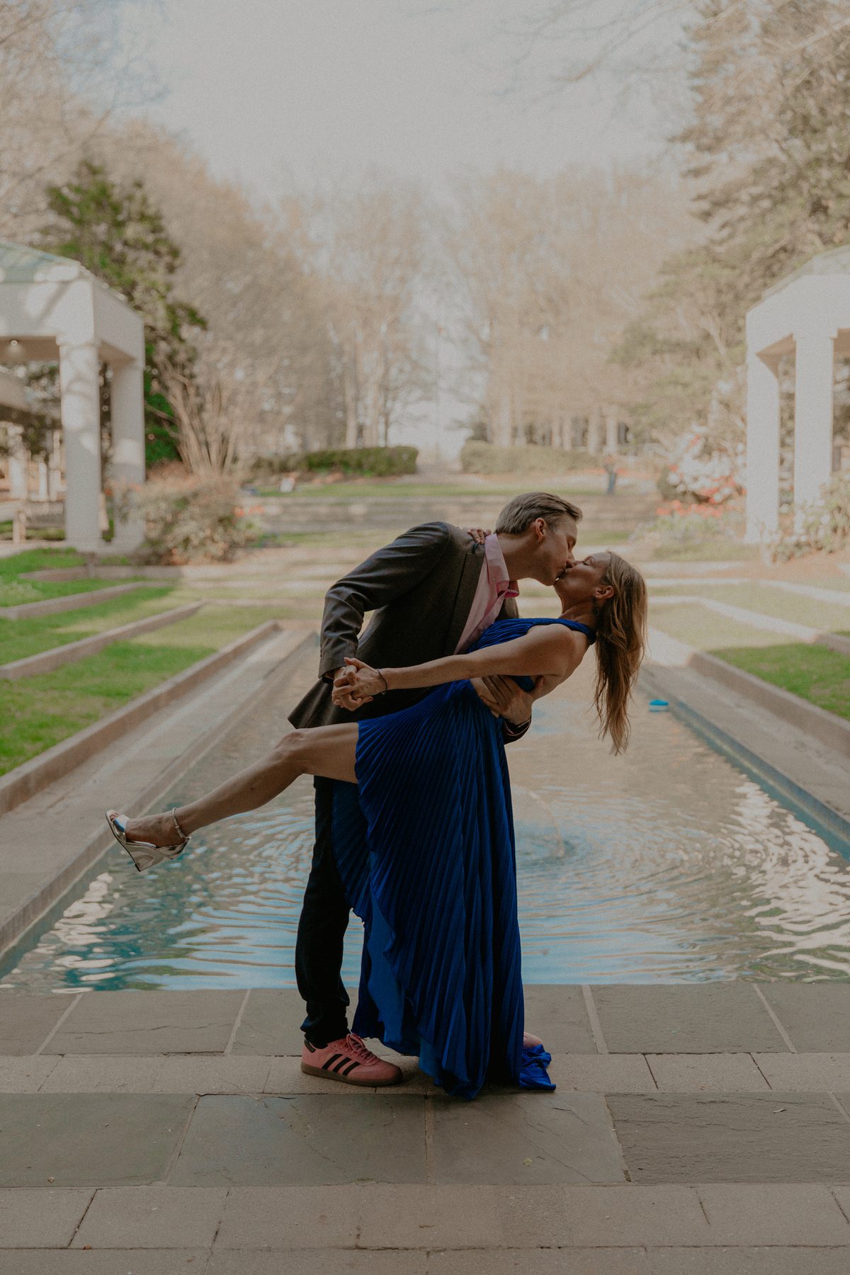 Ian dipping Kimberly for a kiss beside a long reflecting pool