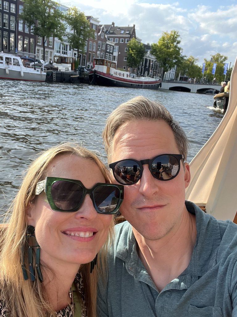 Kimberly and Ian in sunglasses on a boat along an Amsterdam canal