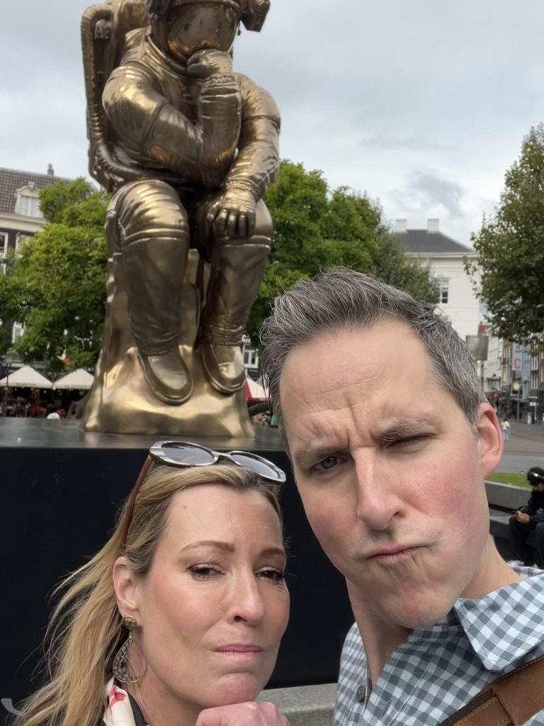 Kimberly and Ian making thoughtful faces in front of a bronze astronaut statue