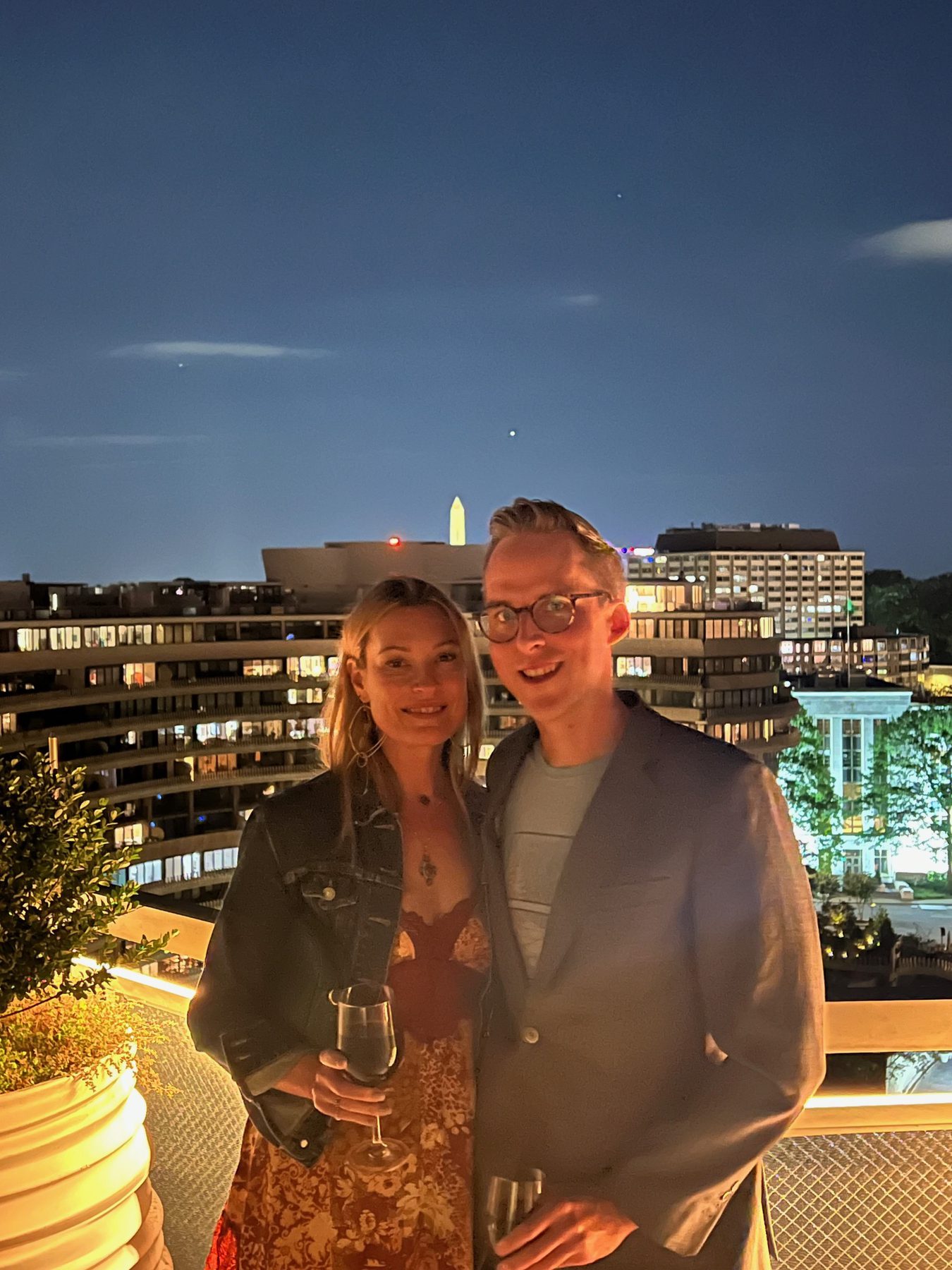 Kimberly and Ian on a rooftop at night with the Washington Monument glowing in the distance