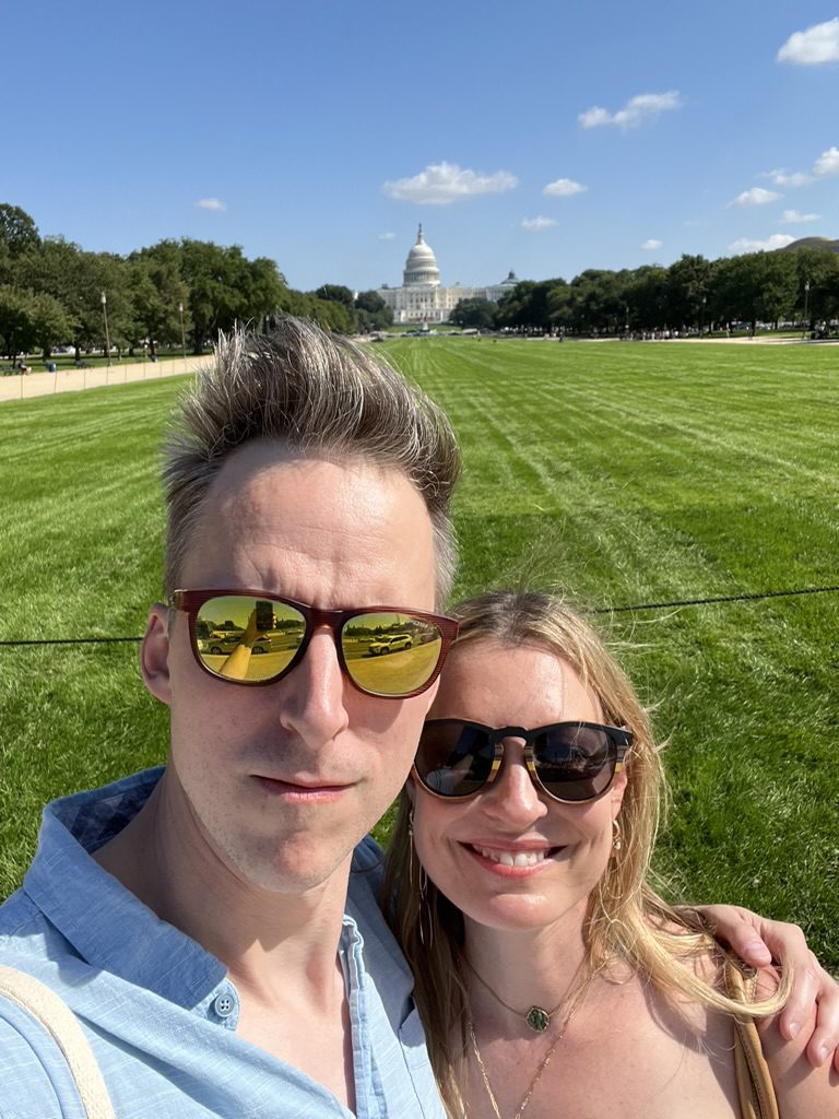 Kimberly and Ian in sunglasses taking a selfie on the National Mall with the U.S. Capitol behind them