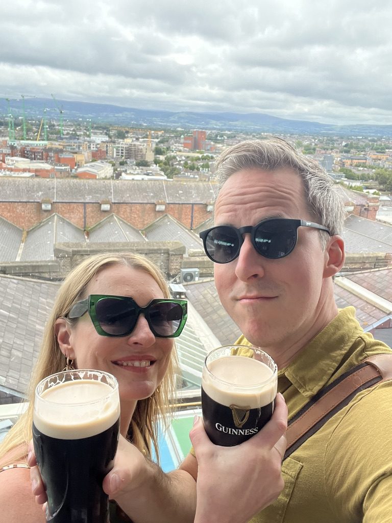 Kimberly and Ian raising pints of Guinness above the rooftops of Dublin