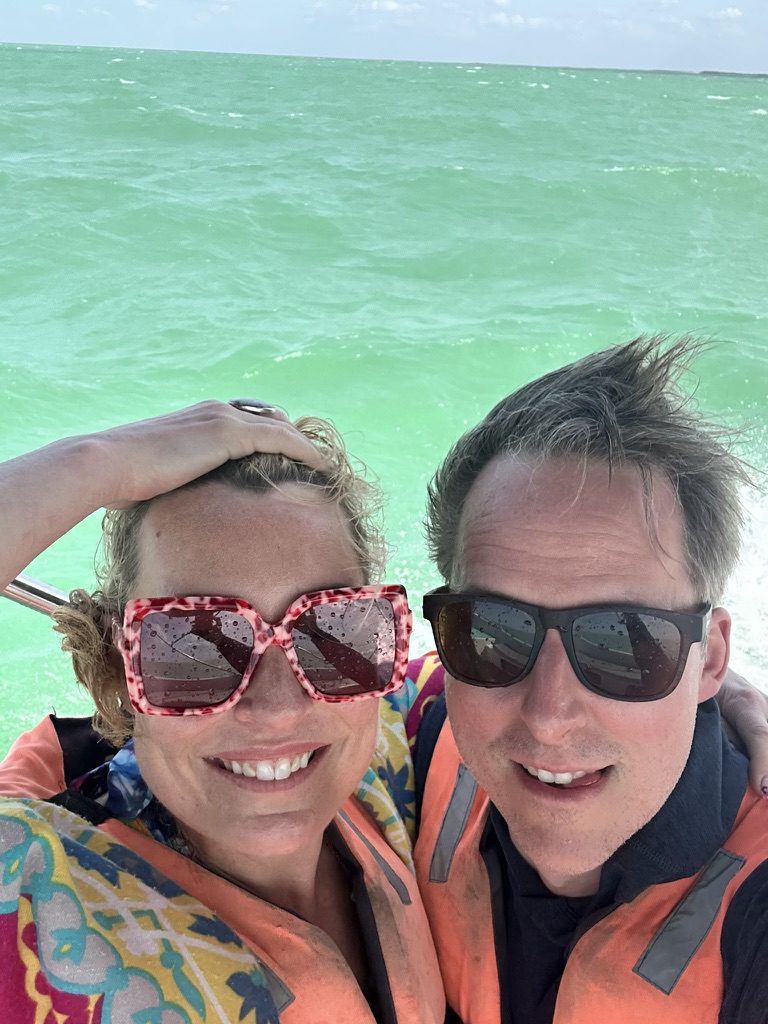 Kimberly and Ian in orange life jackets on a boat over turquoise water