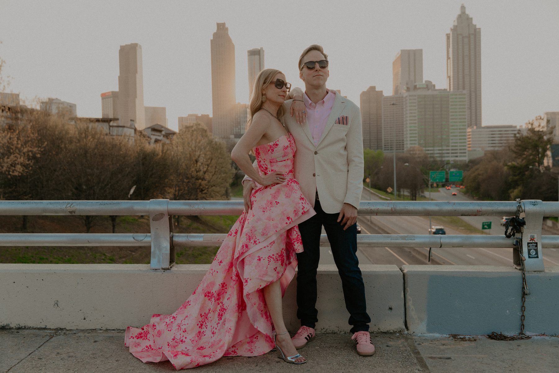 Kimberly and Ian in sunglasses posing on a bridge with the Atlanta skyline behind them